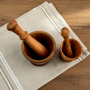 Walnut wood mortar with fresh spices and herbs on modern kitchen table
